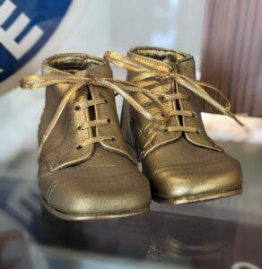 Paar goldene Babyschuhe aus Leder mit Schnürung - elegante Erstlingsschuhe mit glänzender Oberfläche.