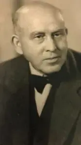 Historisches Porträtfoto eines Herrn im dunklen Anzug mit Fliege, aufgenommen in den 1940er oder 1950er Jahren.