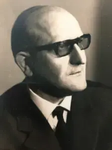 Porträtfoto eines älteren Herrn im dunklen Anzug mit Sonnenbrille, vermutlich aus den 1960er oder 1970er Jahren.